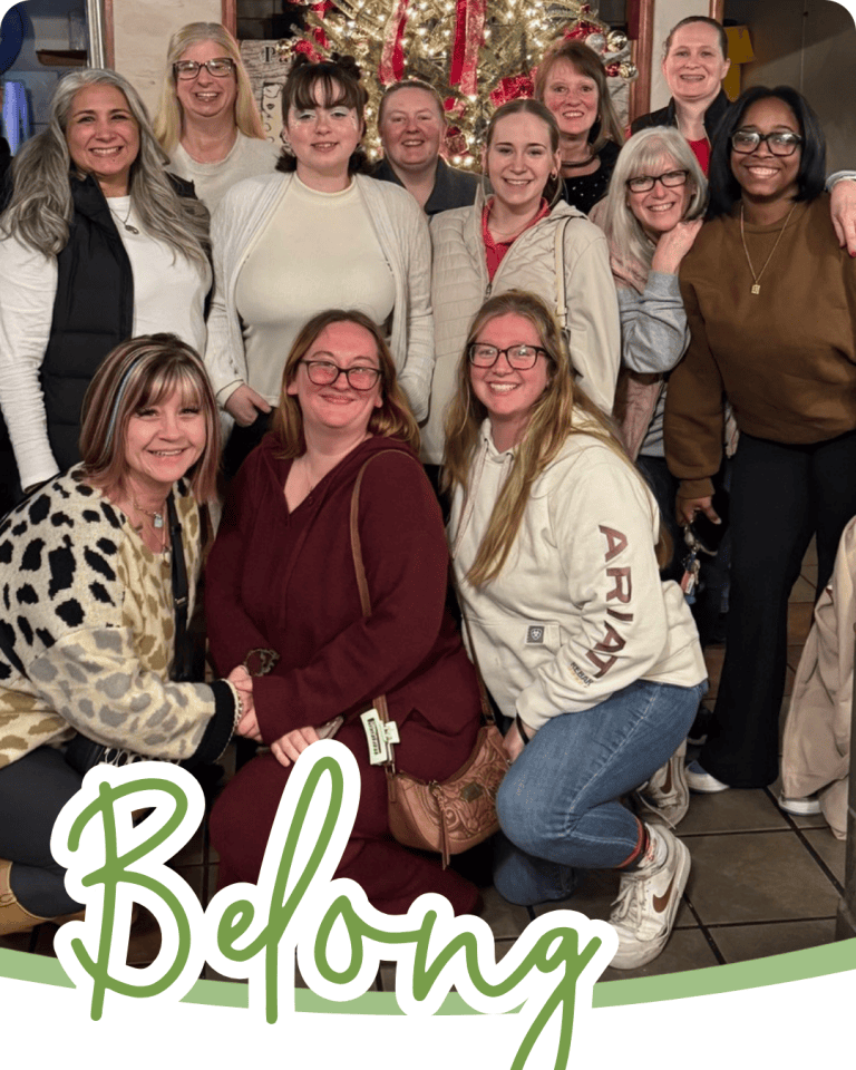 A group of women posed together in a group with the word belong in green script font below