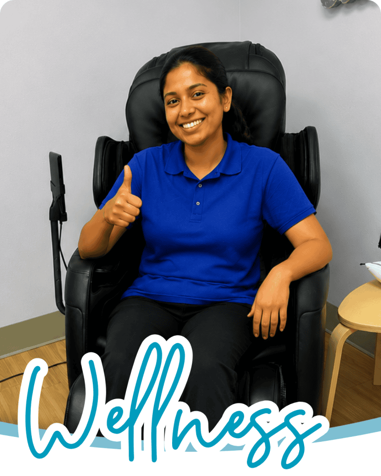 image of a woman in a massage chair smiling with one of her thumbs up, the word wellness in blue script font below
