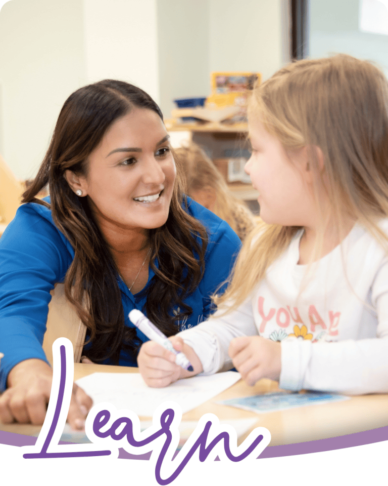image of a pre-k teacher and a child at a table learning together the child is holding a marker and the teacher is pointing at the paper, they are smiling at each other and the word learn is below in a purple script font